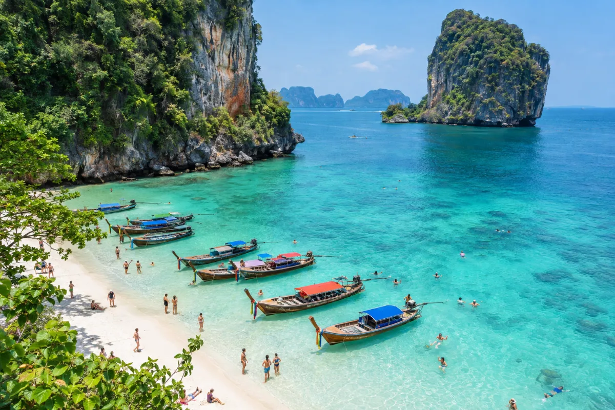 Vit sandstrand med longtailbåtar i Krabi sedd från ovan